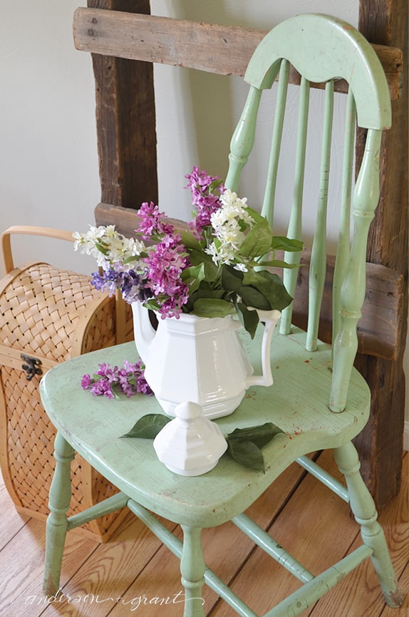 white ironstone teapot filled with lilacs on painted chair